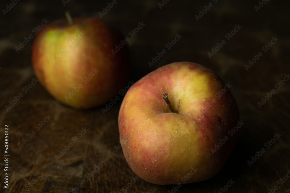 Gold Reinette apple, an old traditional variety of fruits in dark, moody setting on wooden table with delicate light.