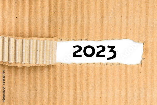 The year 2023 on torn paper, background for office supplies.