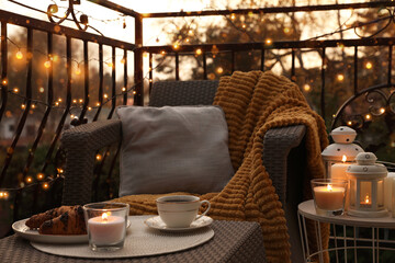 Beautiful view of garden furniture with pillow, soft blanket and burning candles at balcony