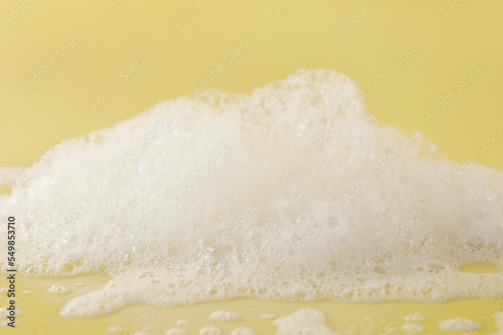 Fluffy bath foam on pale orange background, closeup Fluffy bath foam on pale orange background, closeup