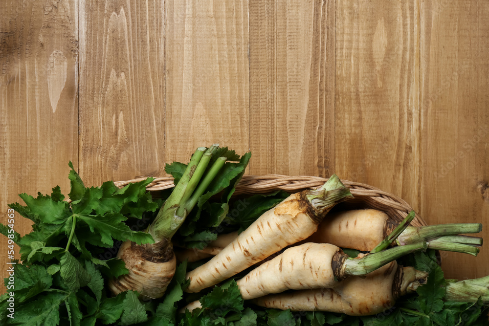 Tasty fresh ripe parsnips in wicker basket on wooden table, top view. Space for text Tasty fresh ripe parsnips in wicker basket on wooden table, top view. Space for text