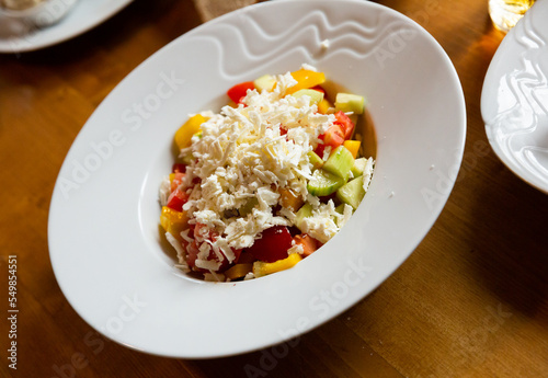 Dish of Balkan cuisine Shopska salad with cucumbers, tomatoes, bell peppers and brynza (salted sheep cheese)