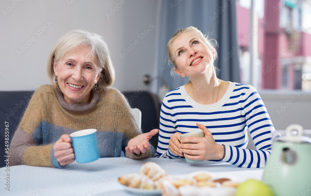 Two women drink tea and eat cakes. Mother with daughter