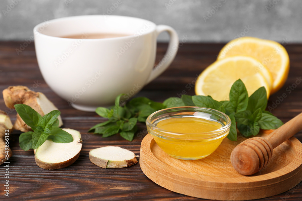 Bowl with honey for tea, lemon, mint and ginger on wooden table Bowl with honey for tea, lemon, mint and ginger on wooden table