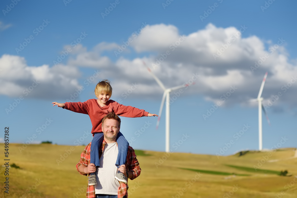 © Maria Sbytova - Eco activists man and child on background of power stations for renewable electric energy production. People and windmills. Wind turbines for generation electricity. Green energy