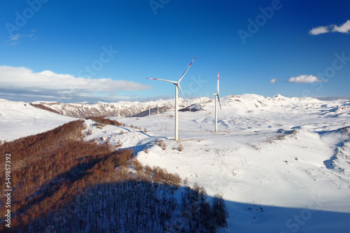 Drone view of power stations for renewable electric energy production. Windmills on sunny winter day. High wind turbines for generation electricity.