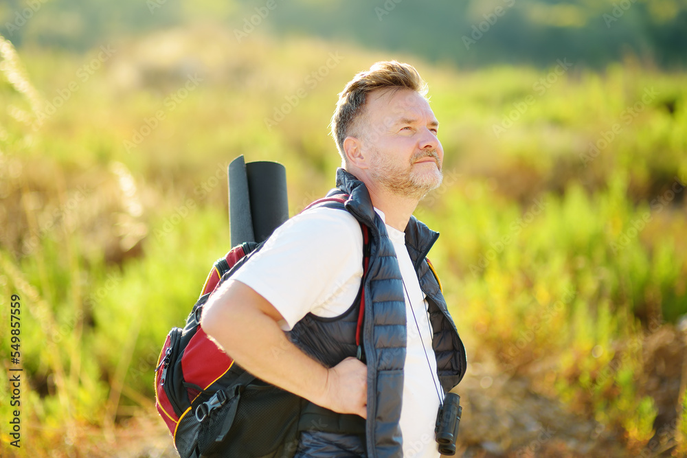 Obraz premium Mature man hiking on sunny summer day. Adventure concept. Solo travel. Hitch-hiking. Backpacking trip