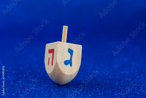 Jewish holiday Hanukkah concept. Wooden dreidel (spinning top) on blue background.