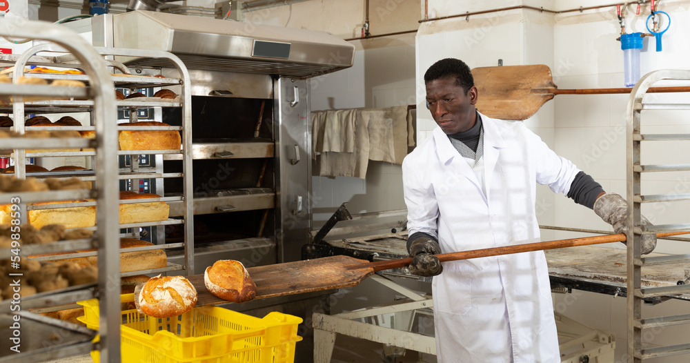 Bakery worker pulls hot bread from the oven. High quality photo