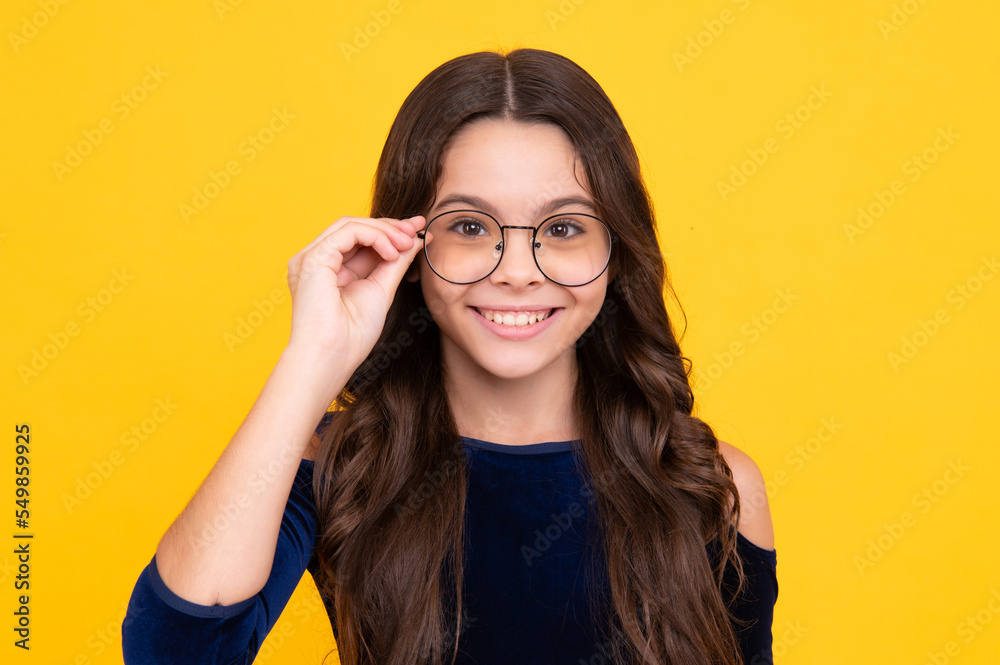 Happy face, positive and smiling emotions of teenager girl. Teenager child wearing glasses on yellow studio background. Cute girl in eyeglasses.