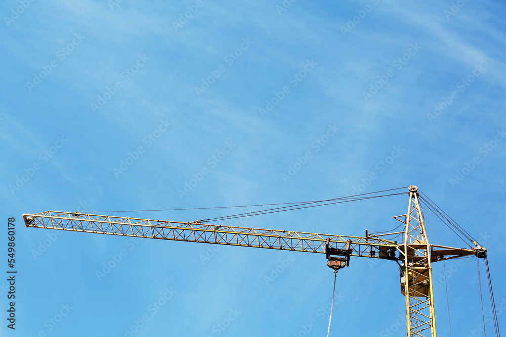Modern tower crane against blue sky. Construction site, low angle view Modern tower crane against blue sky. Construction site, low angle view