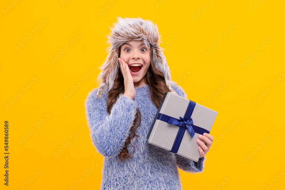 shocked teen girl wear earflap hat with purchase ox on yellow background, holiday shocked teen girl wear earflap hat with purchase ox on yellow background, holiday