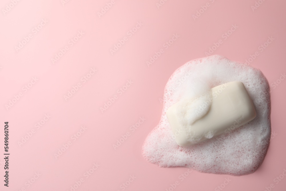 Soap with fluffy foam on pink background, top view. Space for text Soap with fluffy foam on pink background, top view. Space for text