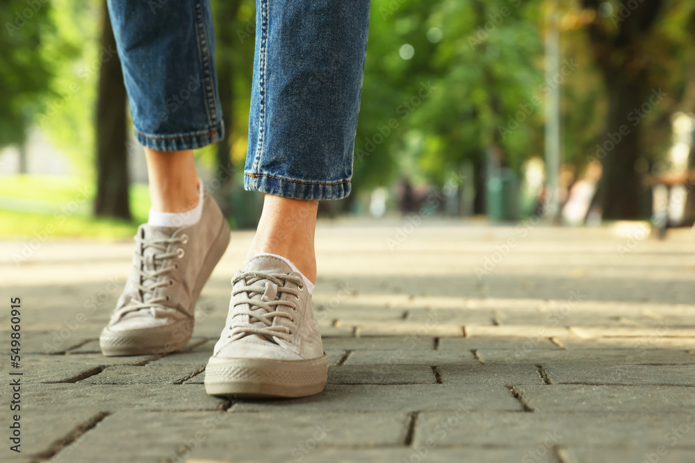 Woman in stylish sneakers walking on city street, closeup. Space for text Woman in stylish sneakers walking on city street, closeup. Space for text