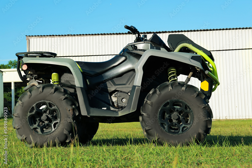 Modern quad bike in field near hangar on sunny day Modern quad bike in field near hangar on sunny day