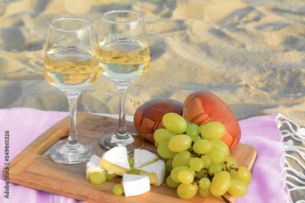 Fototapeta premium Glasses with white wine and snacks for beach picnic on sand outdoors