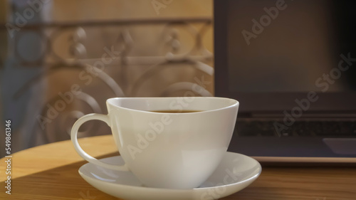 Fototapeta Naklejka Na Ścianę i Meble -  Cup of aromatic coffee and laptop on wooden table outdoors, closeup