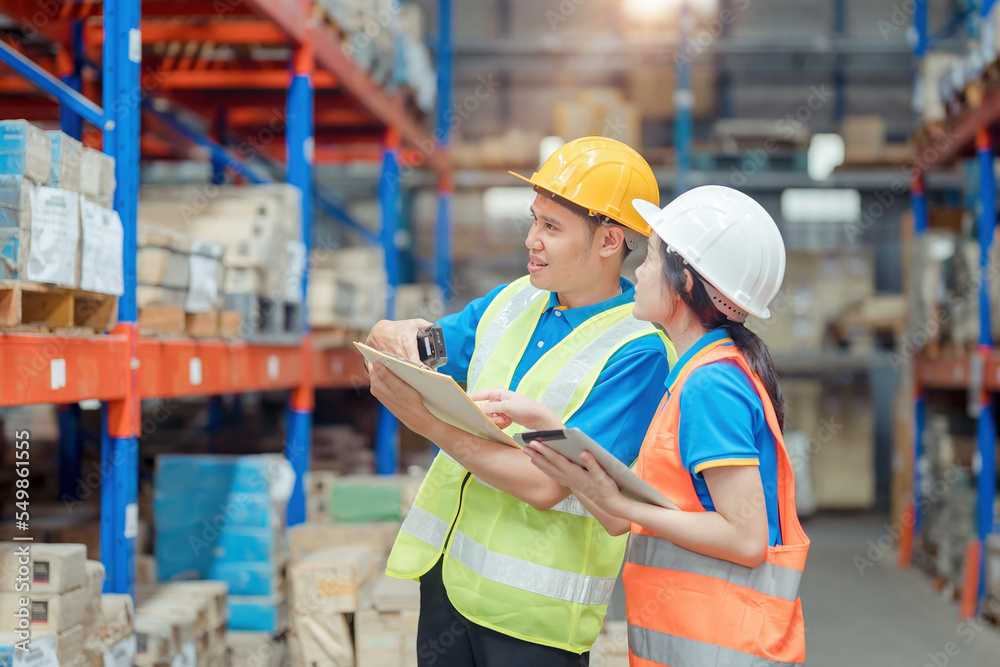 Asian engineer in helmets order and checking goods and supplies on shelves with goods background in warehouse.logistic and business export ,Warehouse worker checking packages on shelf in a large store Asian engineer in helmets order and checking goods and supplies on shelves with goods background in warehouse.logistic and business export ,Warehouse worker checking packages on shelf in a large store