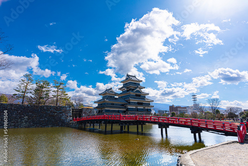 晴天の日に撮影した松本城と赤い橋とお堀の水と石垣（お堀に逆さ松本城が映る）