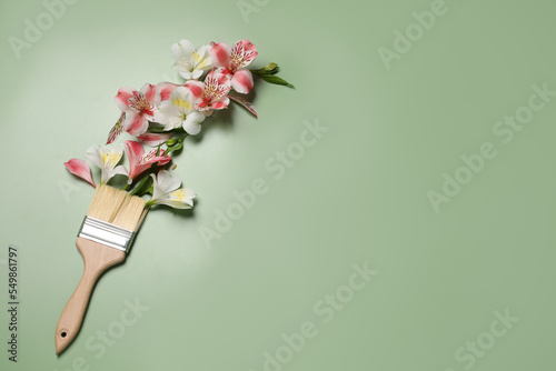 Composition with painting brush and beautiful alstroemerias on green background, above view. Space for text photo