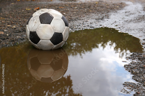 Dirty soccer ball in muddy puddle  space for text