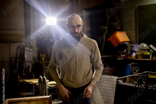 Guy in carpentry shop. Young man with bald head. Indoor woodworker.