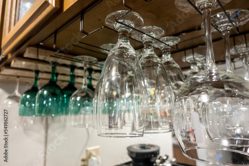 Close up view of wine glasses hanging above a bar counter inside a residential home © ColleenMichaels