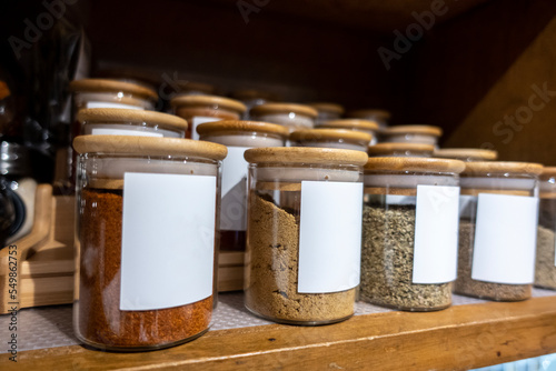 Selective focus on blank labeled seasoning jars inside a cupboard in a home kitchen
