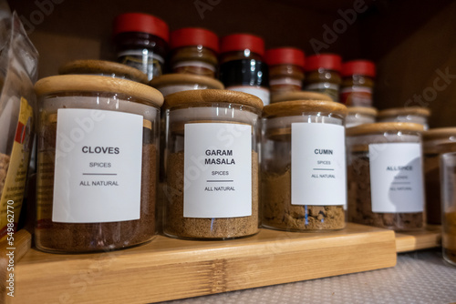 Selective focus on blank labeled seasoning jars inside a cupboard in a home kitchen