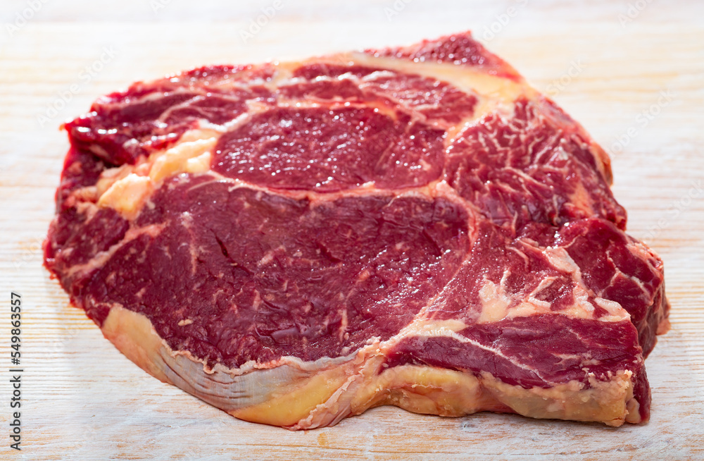 Obraz premium Close up of uncooked beef chop on wooden background