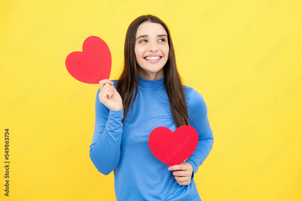 Portrait of pretty smiling woman holding paper heart in her hands on yellow background. Love concept. Portrait of pretty smiling woman holding paper heart in her hands on yellow background. Love concept.