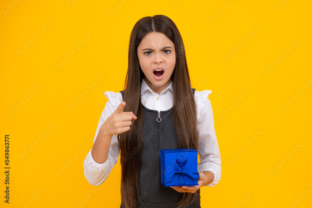 Child with gift present box on isolated studio background. Gifting for kids birthday. Unhappy upset teenager girl. Child with gift present box on isolated studio background. Gifting for kids birthday. Unhappy upset teenager girl.