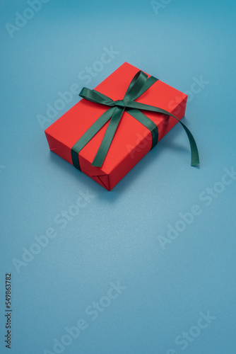 Red gift box on a blue background. Christmas and New Year's decor. Copy space.