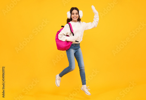 School girl teenager child student with backpack and warn hat, isolated background. Jump and run, jumping kids. Learning and knowledge education concept.