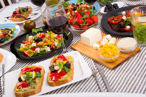 Delicious variety of vegetarian products and dishes with wine on striped fabric background .