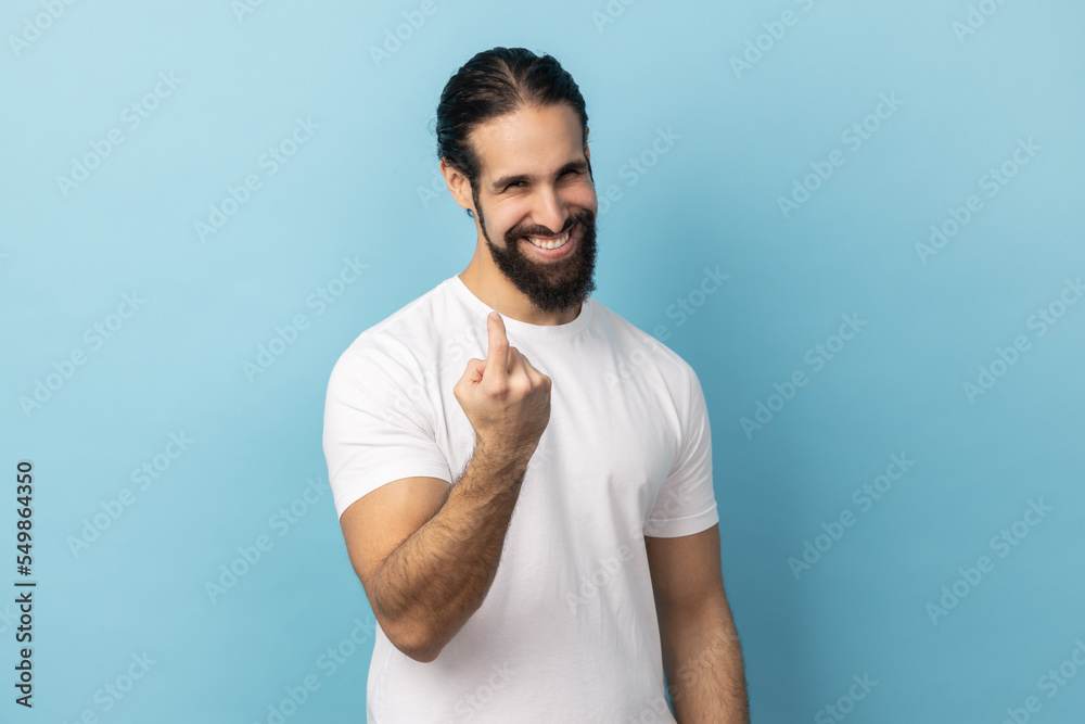 Portrait of positive man with beard wearing white T-shirt doing beckoning gesture, calling inviting to approach, smiling and flirting. Indoor studio shot isolated on blue background. Portrait of positive man with beard wearing white T-shirt doing beckoning gesture, calling inviting to approach, smiling and flirting. Indoor studio shot isolated on blue background.