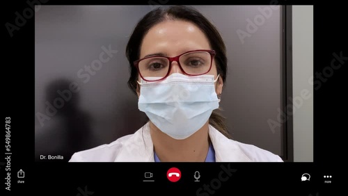 Close up of doctor wearing surgical mask video chatting on computer / Salt Lake City, Utah, United States photo