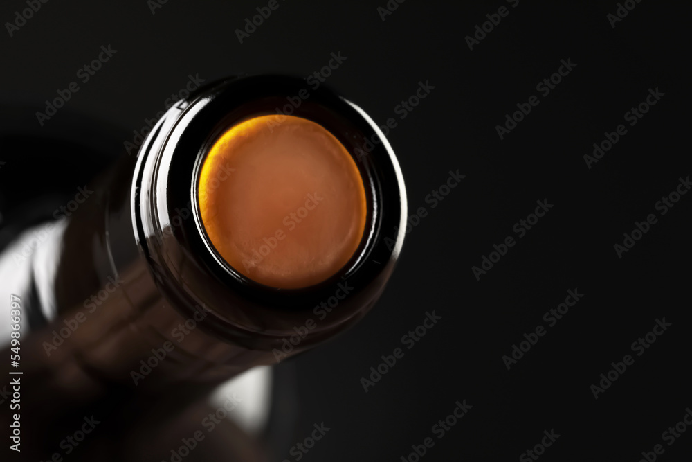 Wine bottle with cork on black background, closeup. Space for text