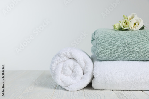Fototapeta Naklejka Na Ścianę i Meble -  Soft towels with flowers on wooden table against white background, space for text