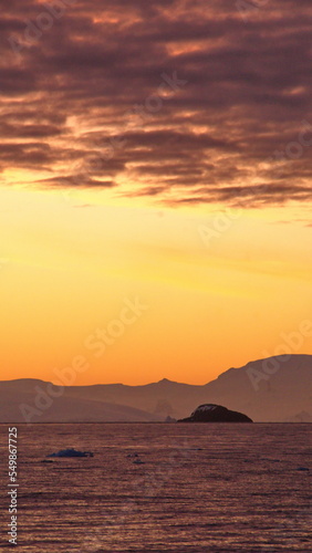 Popcorn clouds illuminated pink over the silhouette of a mountain, at sunset at Cierva Cove, Antarctica © Angela