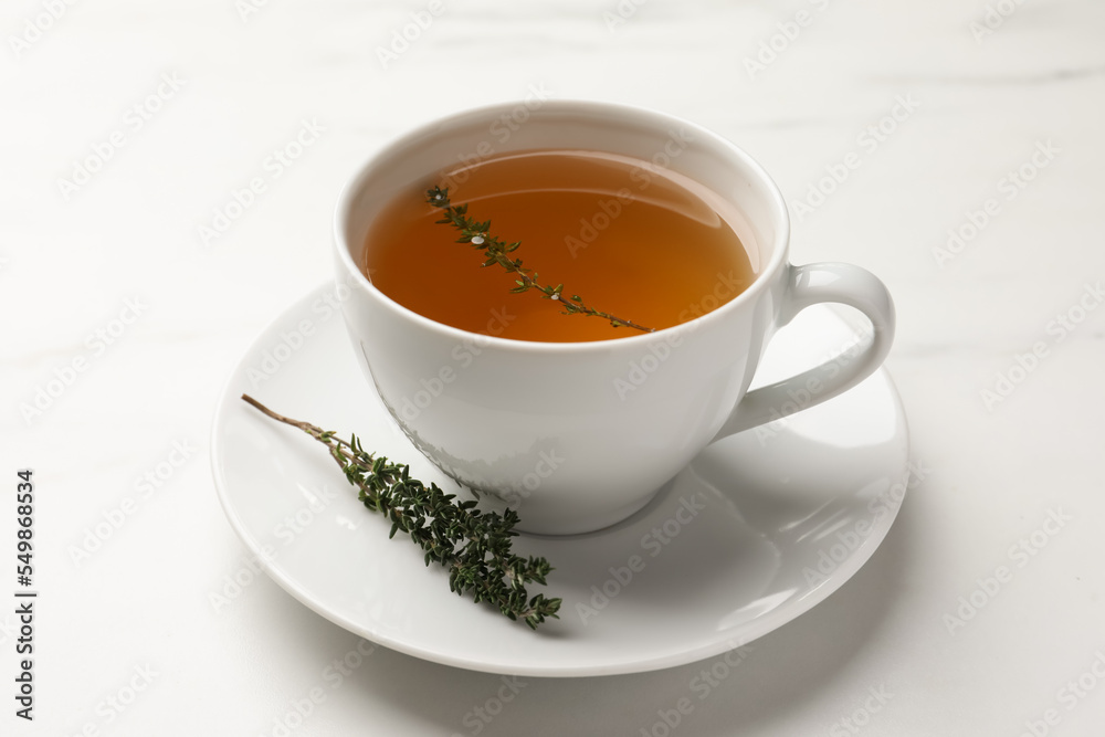 Cup of aromatic herbal tea with thyme on white table Cup of aromatic herbal tea with thyme on white table
