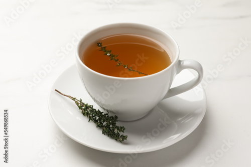 Cup of aromatic herbal tea with thyme on white table