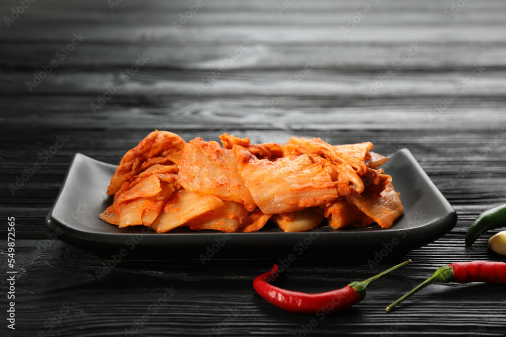 Delicious kimchi with Chinese cabbage and red chili peppers on black wooden table Delicious kimchi with Chinese cabbage and red chili peppers on black wooden table
