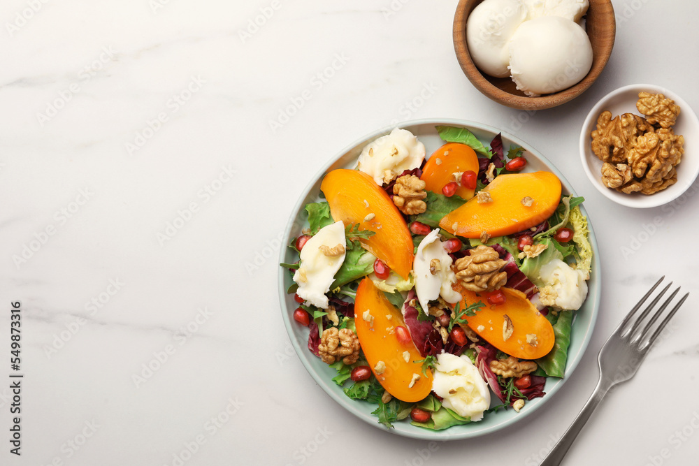 Delicious persimmon salad with cheese and pomegranate served on white marble table, flat lay. Space for text Delicious persimmon salad with cheese and pomegranate served on white marble table, flat lay. Space for text