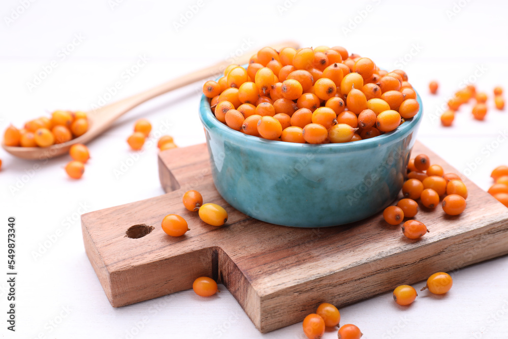 Bowl with fresh ripe sea buckthorn berries on white wooden table Bowl with fresh ripe sea buckthorn berries on white wooden table