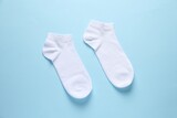 Pair of white socks on light blue background, flat lay