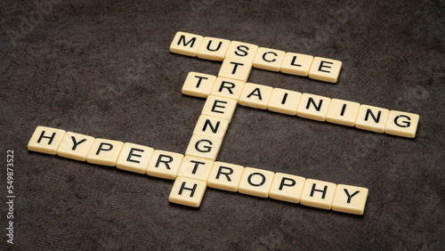 muscle, training for strength and hypertrophy crossword in ivory letter tiles against textured bark paper, fitness concept photo