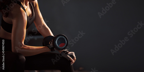 Fototapeta Naklejka Na Ścianę i Meble -  Sporty woman holding weight dumbbell doing fitness workout in the gym.