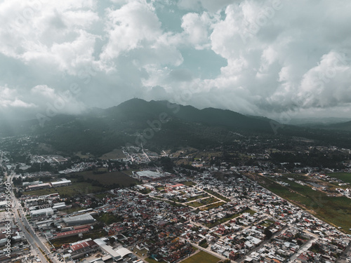 Aerial view of a large mountain at sunset with sun rays breaking through the clouds. The beautiful city 
 San Cristóbal de Las Casas in Mexico.