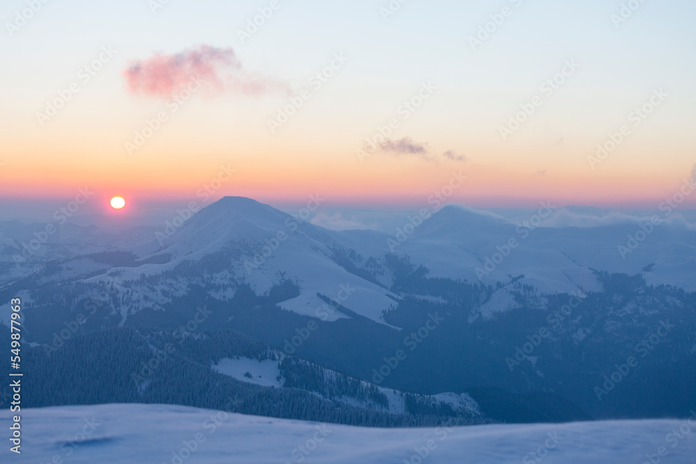 The sun disk rises above a snow-covered mountain at dawn. Petros and Hoverla Peaks The sun disk rises above a snow-covered mountain at dawn. Petros and Hoverla Peaks